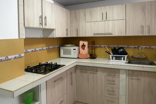 a kitchen with white cabinets and a stove and a microwave at Habitación cómoda en Quito in Quito
