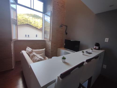 a living room with a white table and a couch at Loft Encantador na Cidade Imperial in Petrópolis