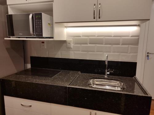 a kitchen counter with a sink and a microwave at Loft Encantador na Cidade Imperial in Petrópolis