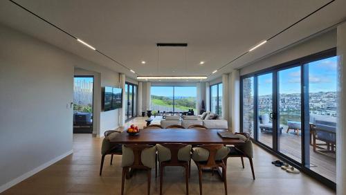 a dining room with a table and chairs and a living room at Sunrise to Sunset Coastal Escape B&B in Auckland
