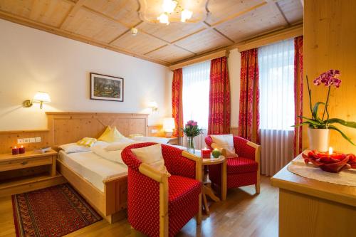 a hotel room with a bed and a table and chairs at Dolomites Wellness Hotel Savoy in La Villa