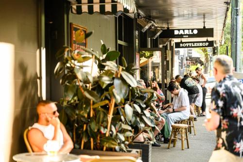 a group of people sitting at tables outside a store at Darlo Bar Darlinghurst in Sydney