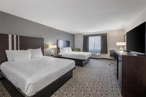 a hotel room with two beds and a flat screen tv at Best Western Pahrump Oasis in Pahrump