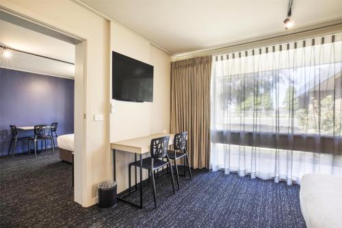 a hotel room with a desk and a bed and a window at Nightcap at Gateway Hotel in Corio