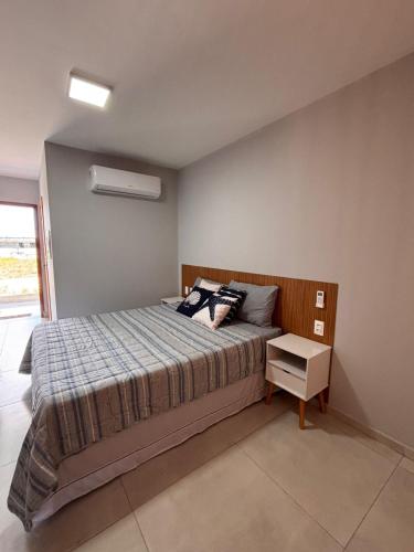 a bedroom with a large bed with a night stand at Barra Grande Flat Manaí in Marau