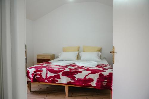 a bedroom with a bed with a red and white blanket at Dikellari Guest House in Pogradec