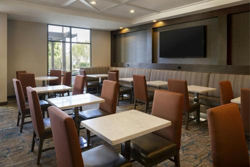 Un comedor con mesas y sillas y un televisor de pantalla plana. en Residence Inn Irvine John Wayne Airport Orange County, en Irvine