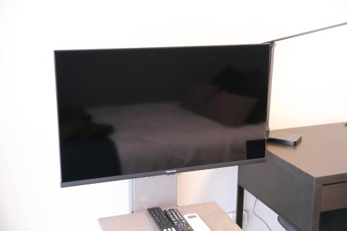 a flat screen tv on a desk with a remote control at シティラデファンス - 2025年6月室内リニューアル in Sapporo
