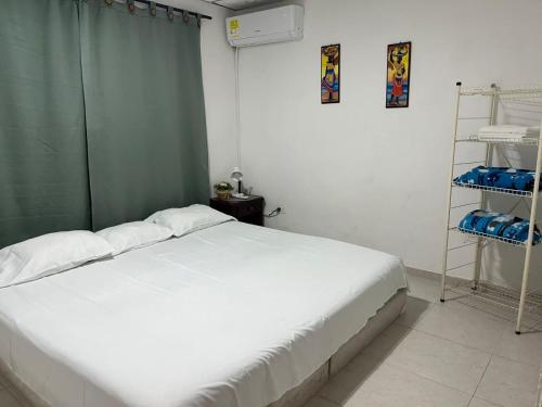 a bedroom with a white bed and a green curtain at Hospedaje Casa Pachi en Cartagena de Indias in Cartagena de Indias