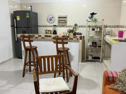 a kitchen with two bar stools and a refrigerator at Hospedaje Casa Pachi en Cartagena de Indias in Cartagena de Indias