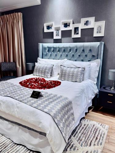 a bedroom with a large bed with a red flower on it at Escapade Lux Guesthouse in Gaborone