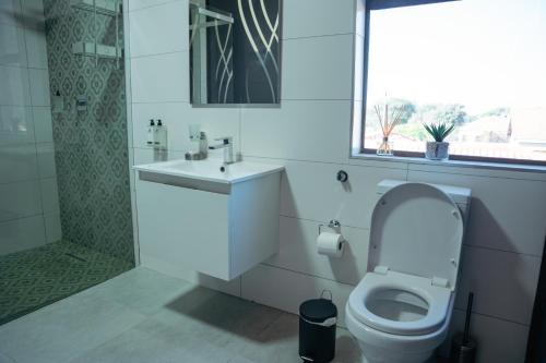 a bathroom with a toilet and a sink and a shower at Escapade Lux Guesthouse in Gaborone
