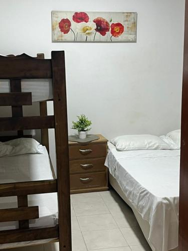 a bedroom with two beds and a dresser and a picture at Hospedaje Casa Pachi en Cartagena de Indias in Cartagena de Indias