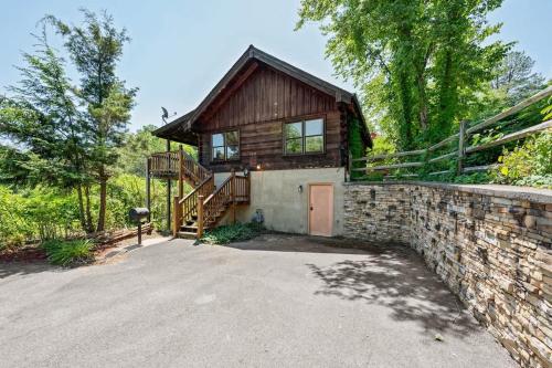 a wooden house with a stone wall and a driveway at Location Smokies Log Cabin Hot Tub Fireplace in Pigeon Forge