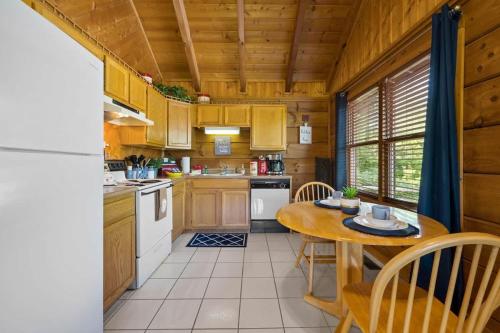 a kitchen with wooden cabinets and a table and chairs at Location Smokies Log Cabin Hot Tub Fireplace in Pigeon Forge