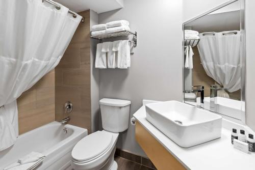 a white bathroom with a toilet and a sink at Hotel Feng, BW Signature Collection in Parksville