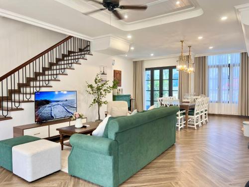 a living room with a green couch and a table at Novaworld Phan Thiết - Ako Villa in Bình Tú