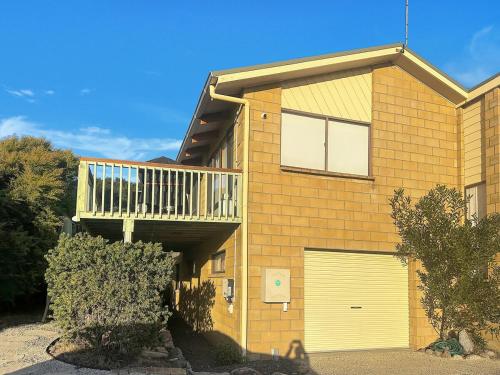 a brick house with a garage and a balcony at High On Coffey - Binalong Bay - Pet Friendly in Binalong Bay