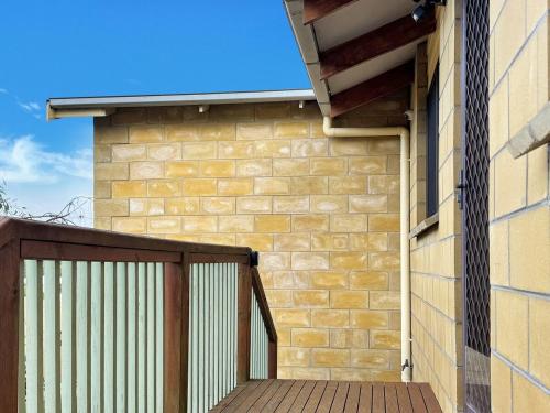 a building with a wooden deck next to a brick wall at High On Coffey - Binalong Bay - Pet Friendly in Binalong Bay