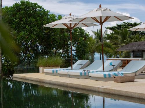 a group of chairs and umbrellas next to a pool at Sava Ocean View Villas in Natai Beach