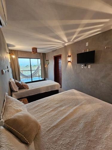 a bedroom with two beds and a flat screen tv at Chalé Duplex Beira Mar Macapá in Luis Correia