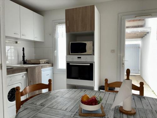 - une cuisine avec une table et un bol de fruits dans l'établissement Charmante maison de vacances à 400m de la plage - FR-1-323-565, à Saint-Hilaire-de-Riez