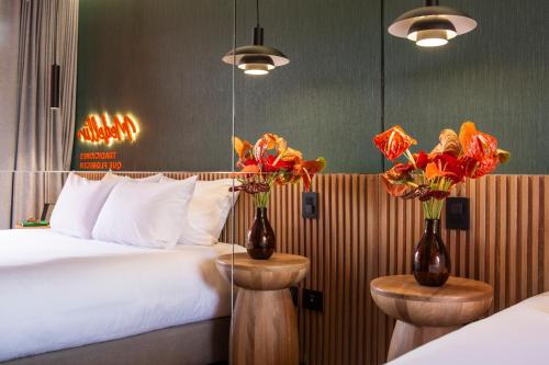a hotel room with a bed and two vases with flowers at Calle Flora Hotel by Jalo in Medellín