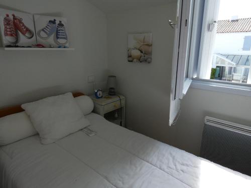 une petite chambre avec un lit blanc et une fenêtre dans l'établissement Charmante maison à 400m de la plage des Demoiselles avec véranda et cour close - FR-1-323-367, à Saint-Hilaire-de-Riez