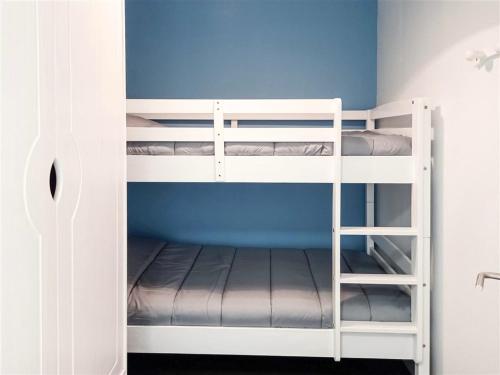 Ce lit se trouve dans un dortoir doté de 2 lits superposés blancs et d'un mur bleu. dans l'établissement Studio cabine avec balcon près des commerces - FR-1-323-424, à Saint-Jean-de-Monts