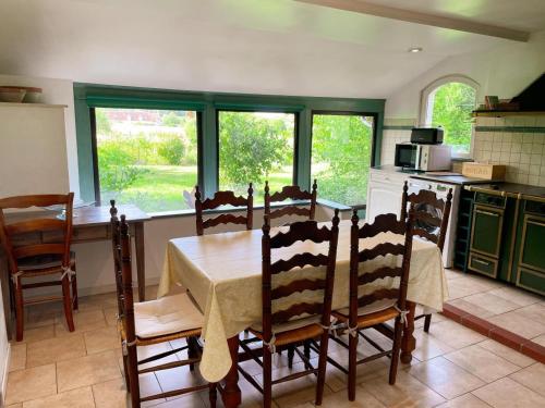 une cuisine avec une table et des chaises et une cuisine avec des fenêtres dans l'établissement Maison 8 min du Zoo de Beauval, jardin, cheminée, tout inclus, proche Châteaux de la Loire - FR-1-491-429, à Châteauvieux