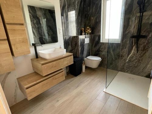 une salle de bain avec un lavabo, des toilettes et un miroir dans l'établissement Villa Rénovée 3 Chambres, Proche Plage avec WiFi, Ménage et Linge Inclus - FR-1-323-507, à Saint-Hilaire-de-Riez