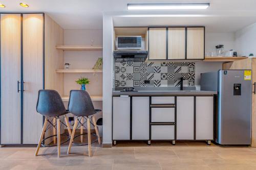 a small kitchen with a refrigerator and two chairs at Edificio Habitare Cristales Cali 2 in Cali