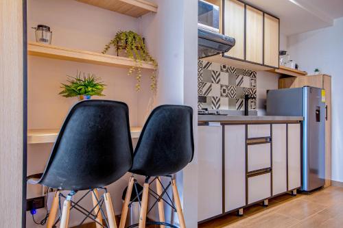 a kitchen with two black stools in front of a counter at Edificio Habitare Cristales Cali 2 in Cali
