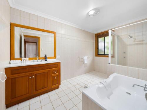 a white bathroom with a sink and a mirror at Pipe Dreams in Arrawarra