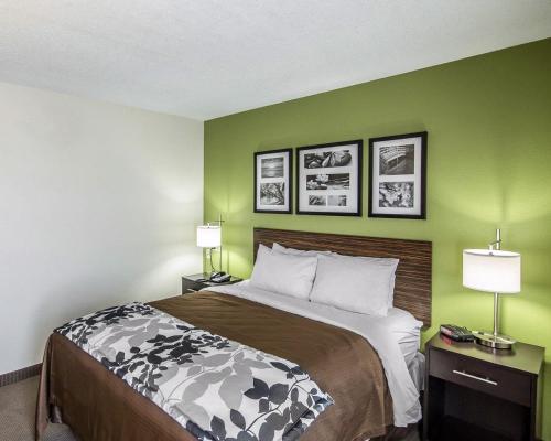 a bed in a hotel room with green walls at Sleep Inn South Joplin in Joplin