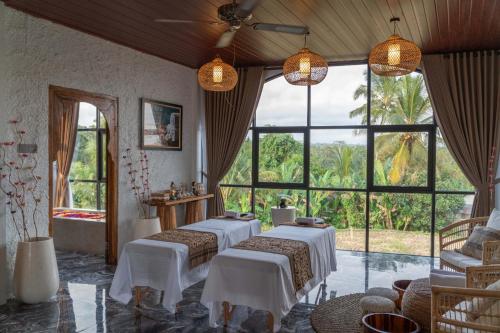 a room with four beds and large windows at Casa Maddu in Tegalalang