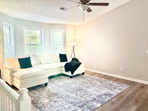a living room with a white couch and a ceiling fan at King Suite - Game Room - Gym - Private Bath - Hot Tub in Ellenwood