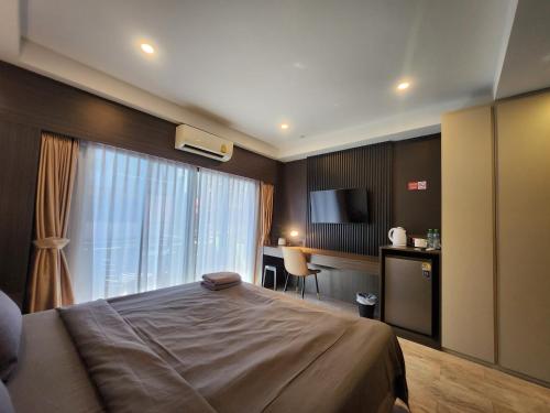a bedroom with a bed and a desk and a television at Max Residence in Pattaya