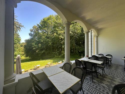an outdoor patio with tables and chairs and a large window at Liselund Ny Slot Hotel in Borre