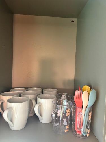 a row of cups and utensils on a shelf at Private Villa Z in Tsumagoi
