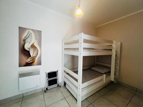 Ce lit superposé blanc se trouve dans un dortoir doté d'un mur. dans l'établissement Appartement T2 Cabine - Balcon - Près de la plage - FR-1-309-513, à Argelès-sur-Mer