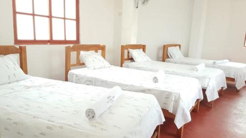 a group of white beds in a room at Hospedaje con vista ala laguna de huacachina refugio en el oasis in Ica