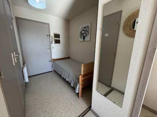Un dormitorio pequeño con una cama y un espejo. en Studio à 400m des plages - 3 couchages - Garage inclus - FR-1-738-50, en Saint-Palais-sur-Mer