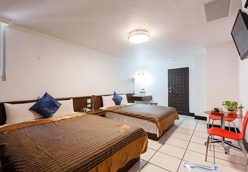a hotel room with two beds and a tv at 登園大飯店 宜蘭縣旅館096號 in Wei-ch'ien