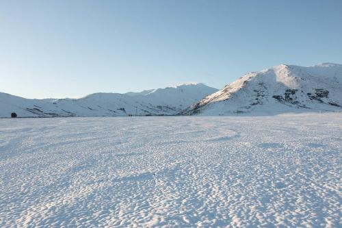 a snow covered field with mountains in the background at 2BR Stay with Fireplace Hot Tub BBQ - Tasman in Lake Tekapo