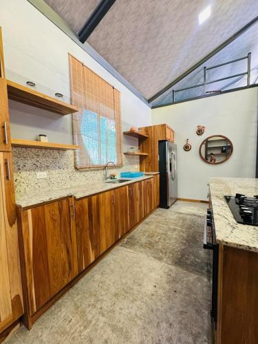a large kitchen with wooden cabinets and a window at Casa Carambola Bioluminicencia, Tortuga y Quesera in Paquera