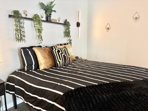 a bedroom with a black and white bed with plants on the wall at Queen Suite - Gym - Game Room - Hot Tub in Ellenwood