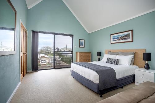 a bedroom with a bed and a large window at Albany Harbourside Apartments And Houses in Albany