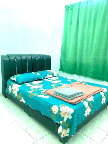 a bed with a blue comforter with flowers on it at Lanang Islamic Homestay in Bedung