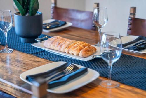 a table with a plate of bread and wine glasses at Soak & Stay Acacia Bay - spa, pet, family friendly in Taupo